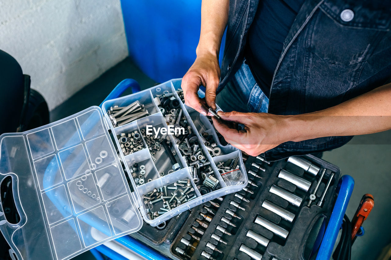 Midsection of mechanic holding with equipment and work tools in garage