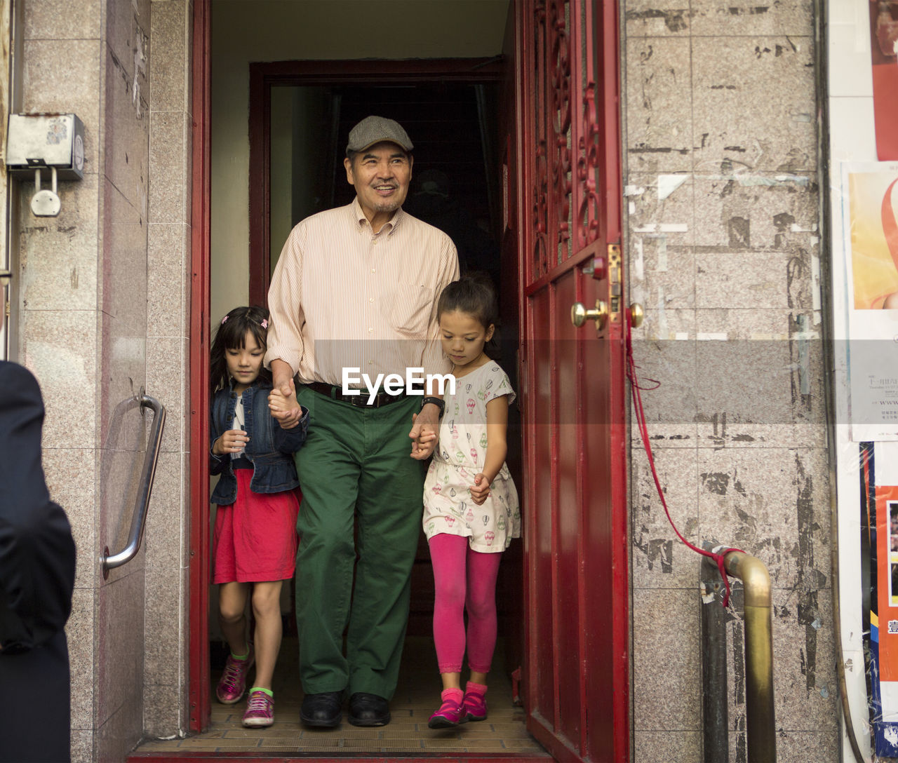 Full length of grandfather and grandchildren walking at doorway