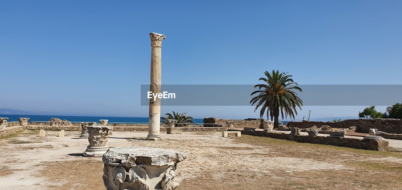 vacation, sky, sea, palm tree, beach, land, water, nature, coast, tropical climate, clear sky, tree, sand, shore, ocean, blue, body of water, day, sunny, travel destinations, plant, no people, architecture, scenics - nature, travel, sunlight, walkway, outdoors, beauty in nature, tranquility, chair, built structure, tourism, tranquil scene, copy space, horizon, horizon over water