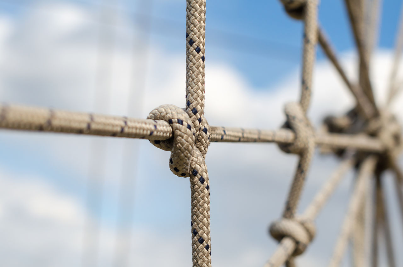 CLOSE-UP OF ROPE TIED TO METAL FENCE