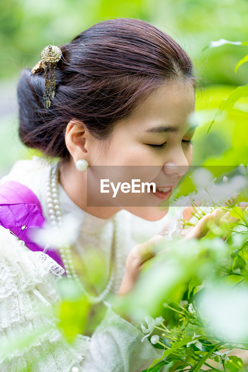 Smiling young woman smelling flowers