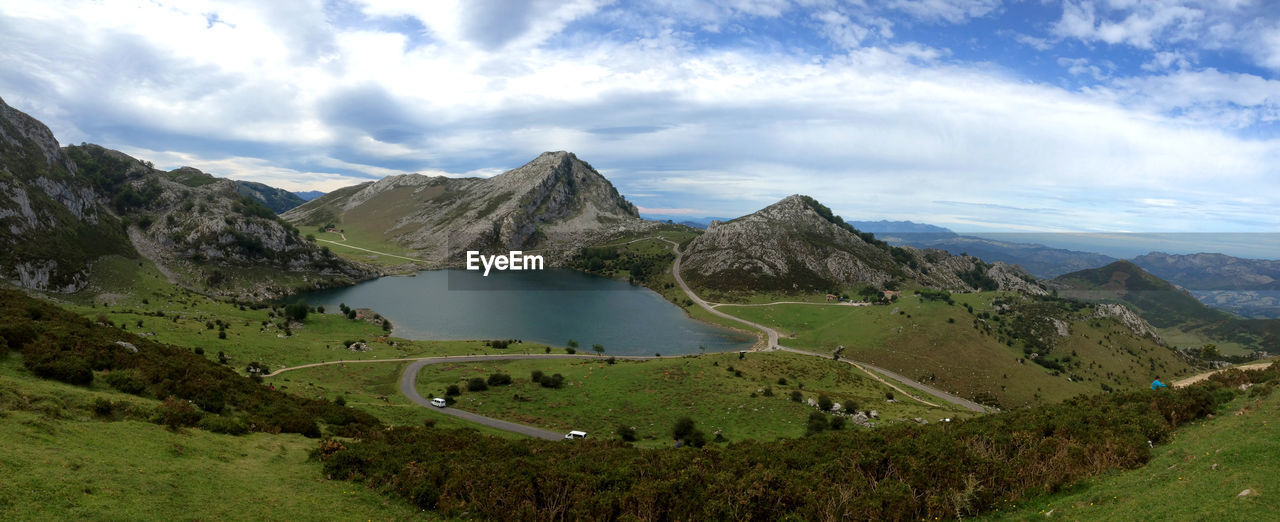 Aerial view of lake enol by mountains against cloudy sky