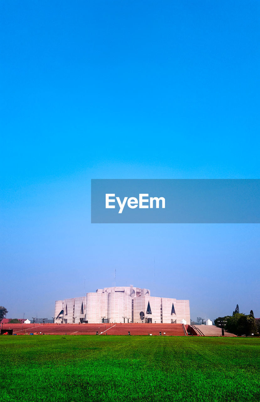 Houses on field against clear blue sky