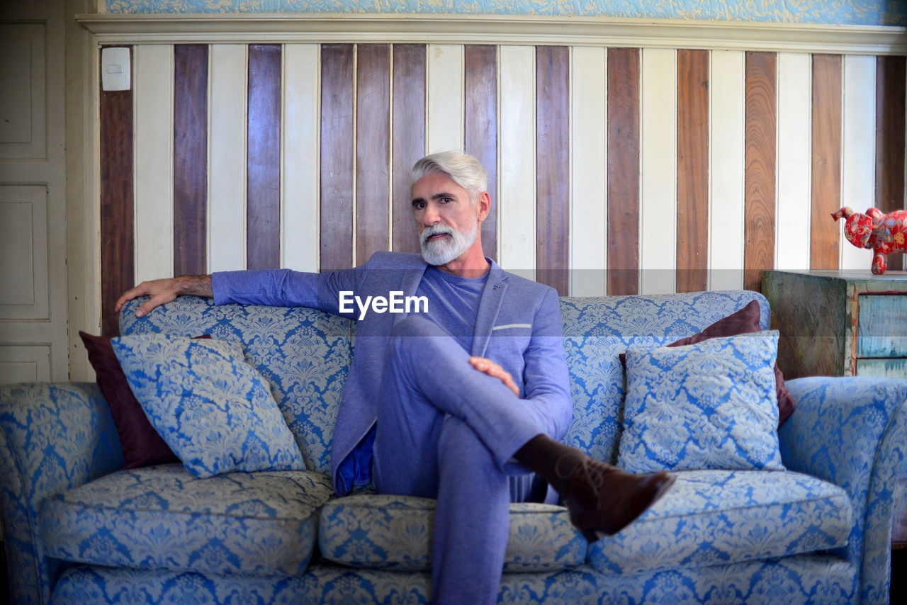 Portrait of a man in suit sitting on sofa at home