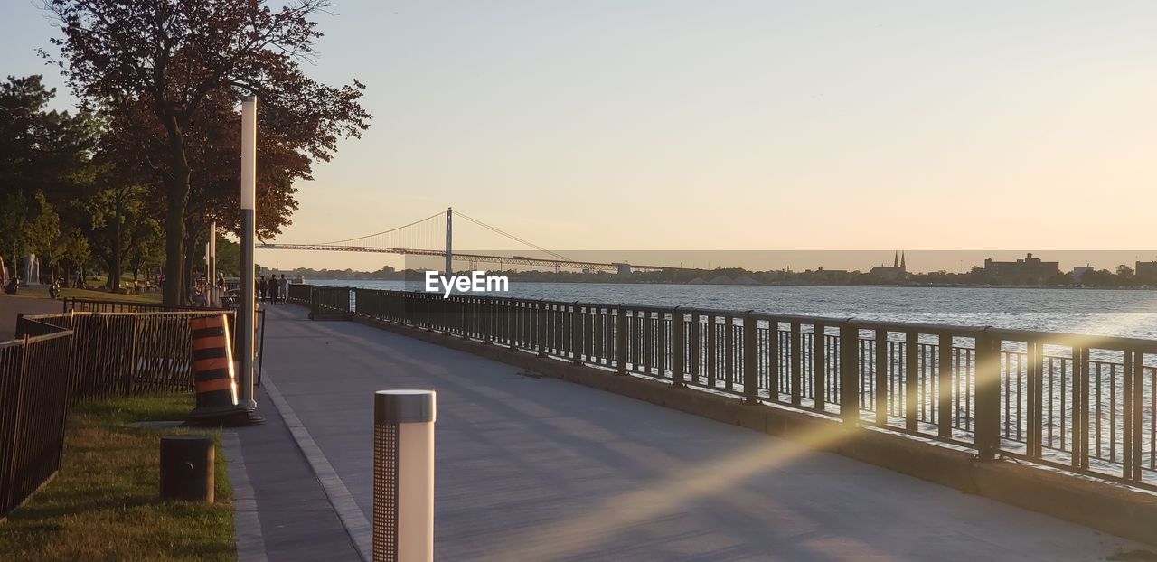 BRIDGE OVER CALM RIVER AT SUNSET