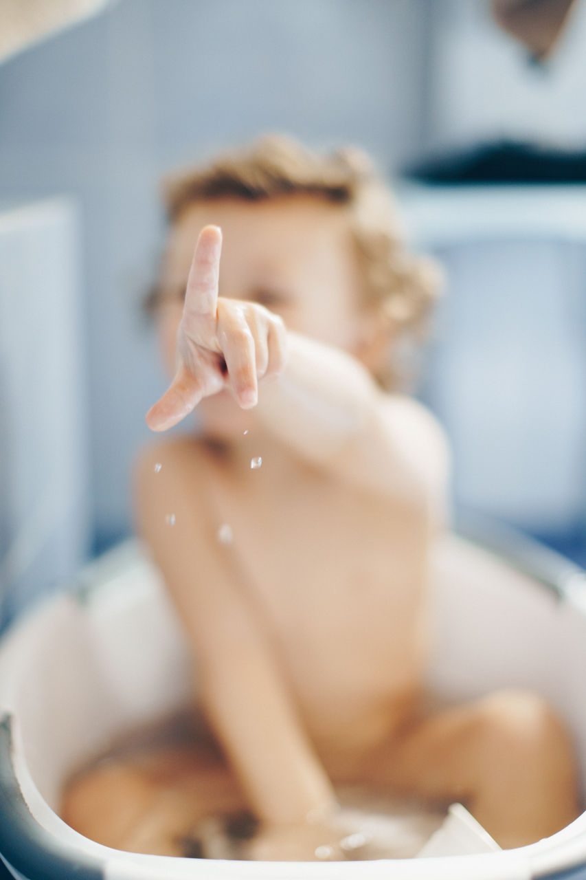 Shirtless girl playing in bathtub