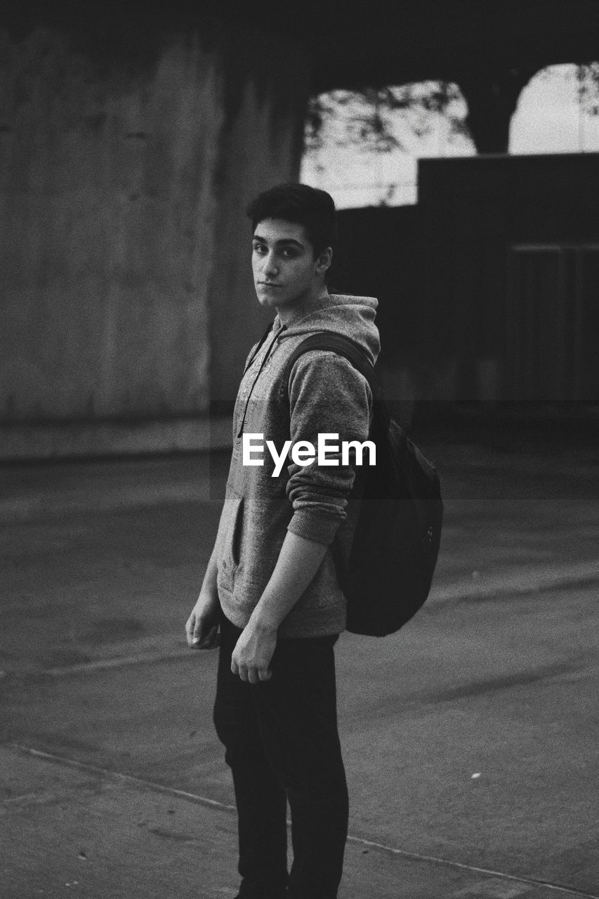 Portrait of young man standing on footpath in city