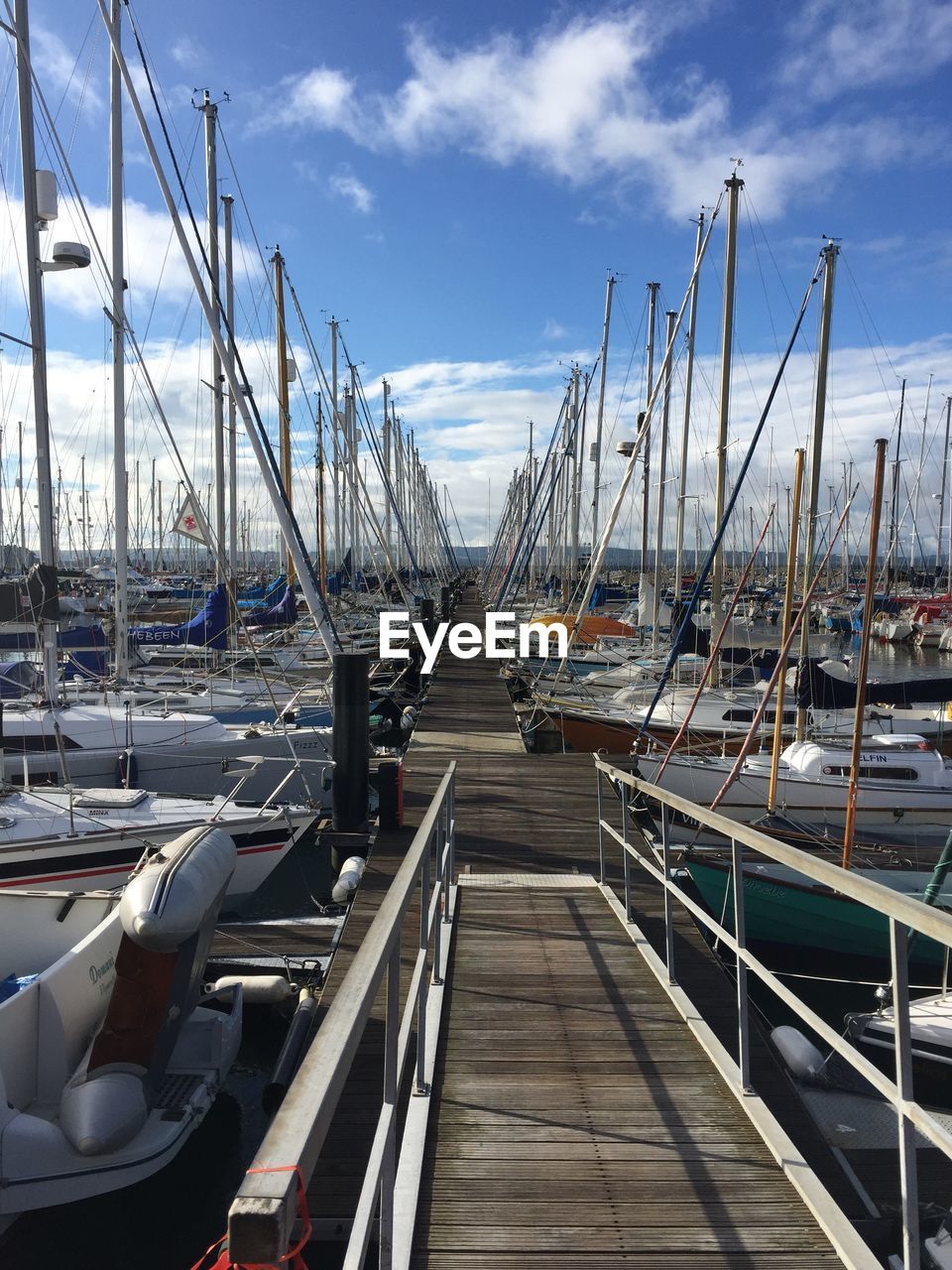 Sailboats moored on harbor against sky