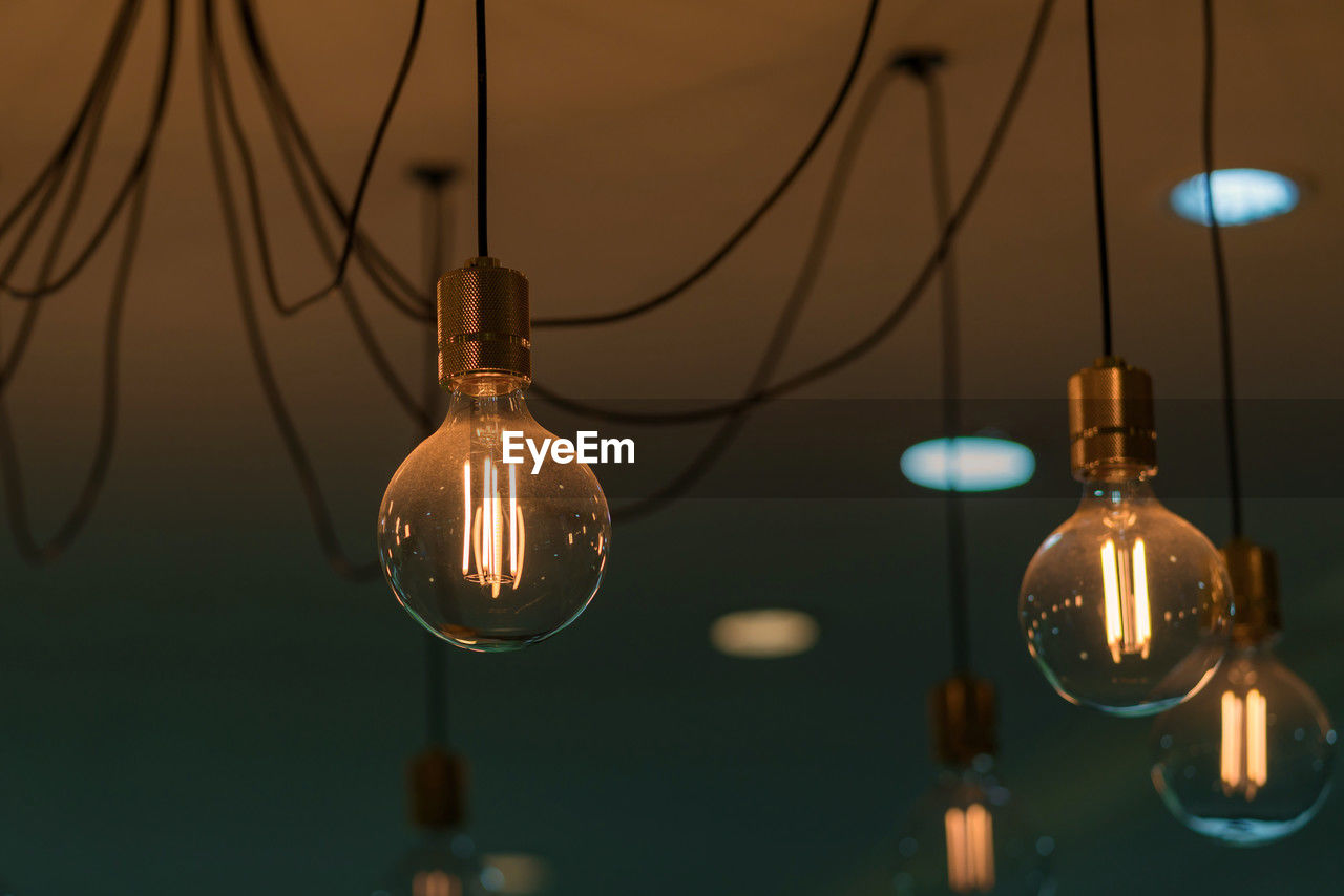 hanging, electricity, lighting equipment, illuminated, light bulb, no people, light fixture, light, chandelier, filament, focus on foreground, indoors, incandescent light bulb, cable, electric light, decoration, close-up, glowing, electric lamp, light - natural phenomenon, pendant light, lighting, night, low angle view, group of objects, ceiling, technology