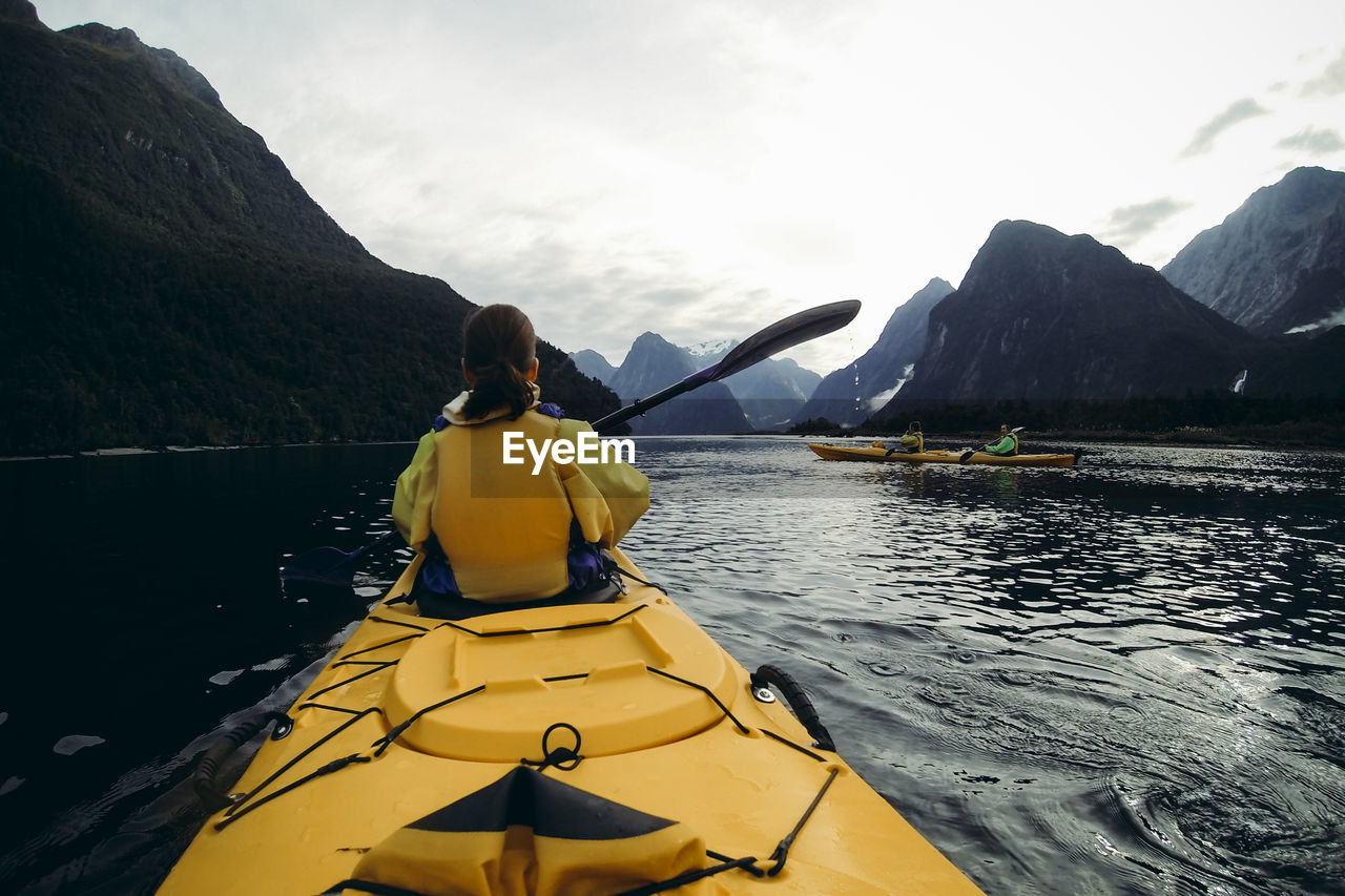 Rear view of woman on lake against mountain range