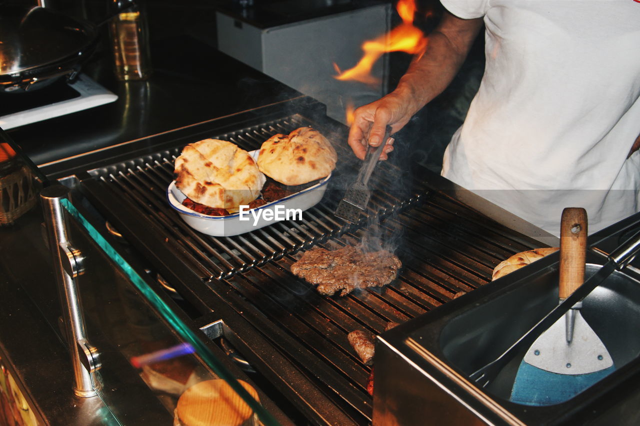 Midsection of man preparing food on barbecue grill