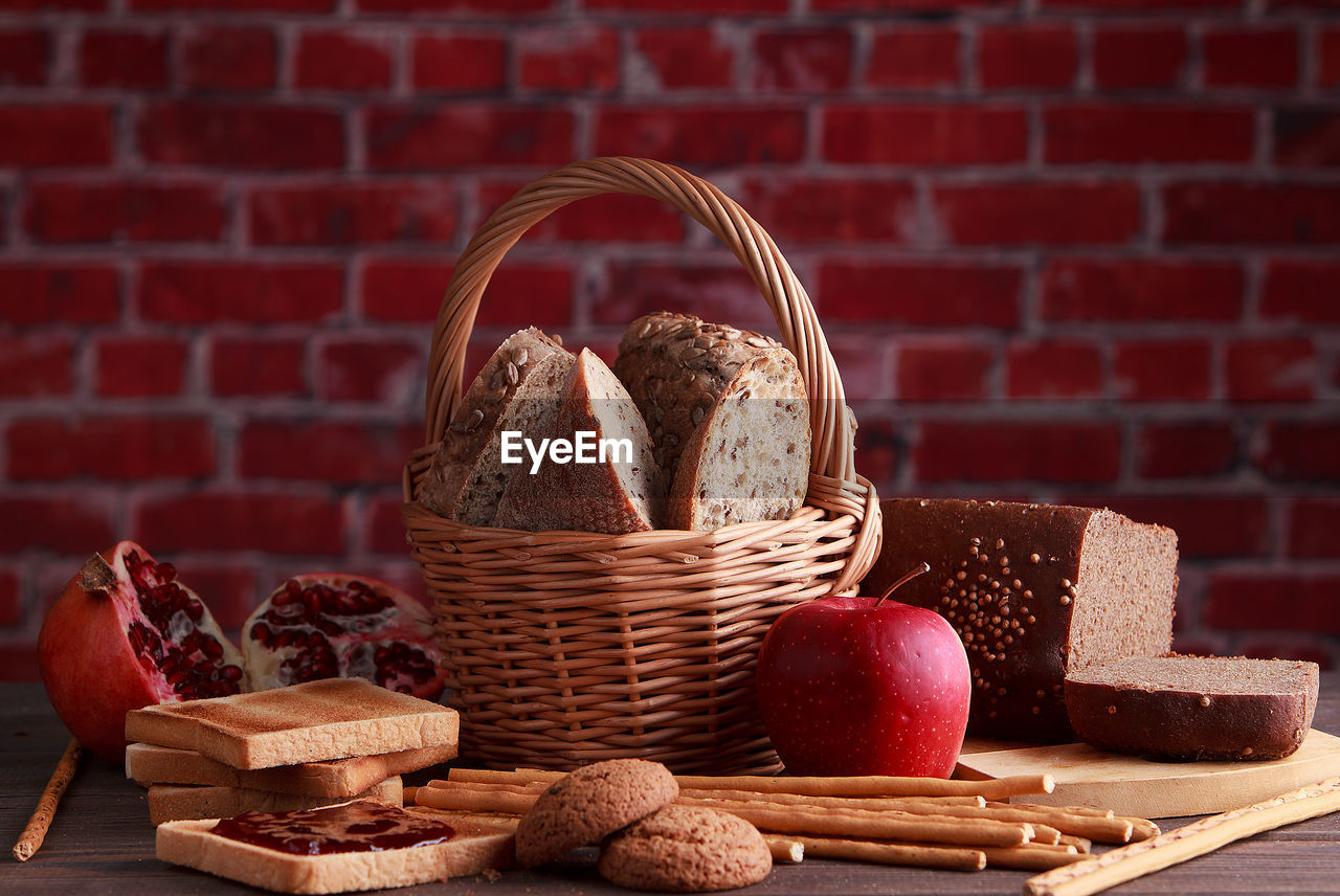 Different buns of fresh bread and spikelets of wheat on a brown vintage background