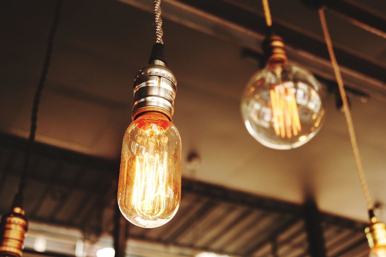 Low angle view of illuminated light bulbs hanging from ceiling