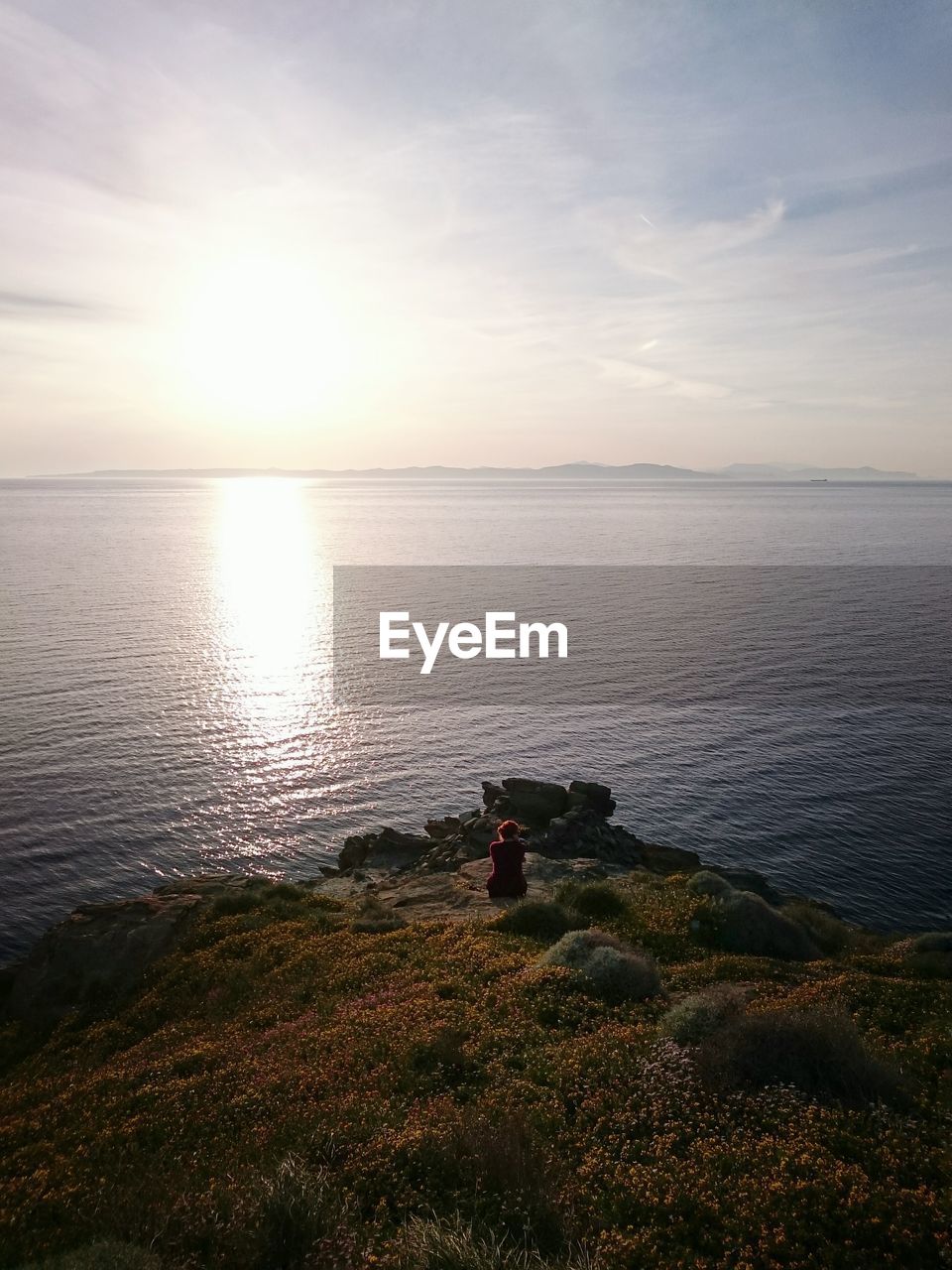 Elevated view of woman looking at sunset over lake