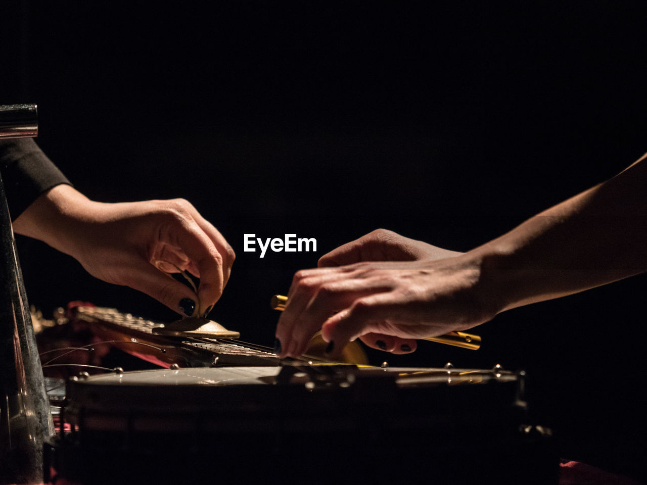 Cropped hands playing music against black background