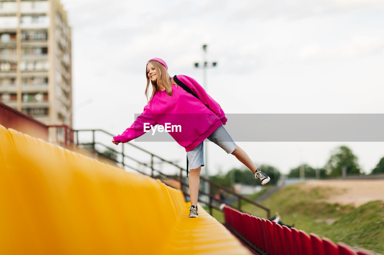 A teenage girl with a backpack walks through the stands of the school stadium