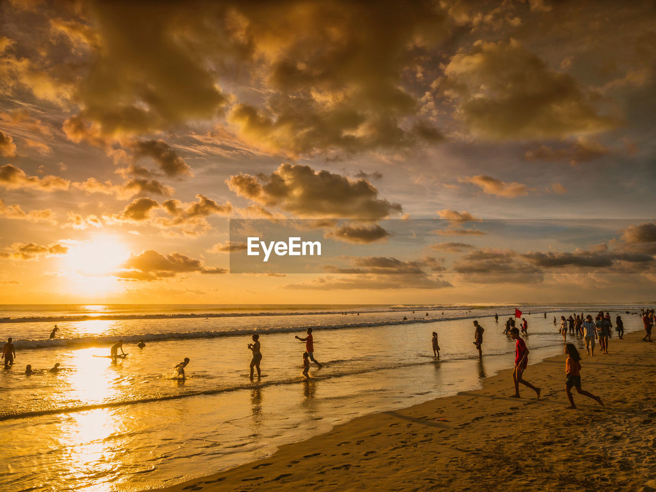 People on beach against sky during sunset