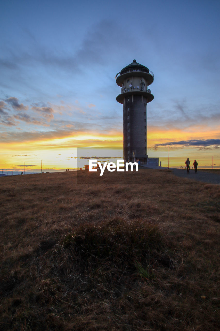 LIGHTHOUSE AMIDST SEA AGAINST SKY DURING SUNSET