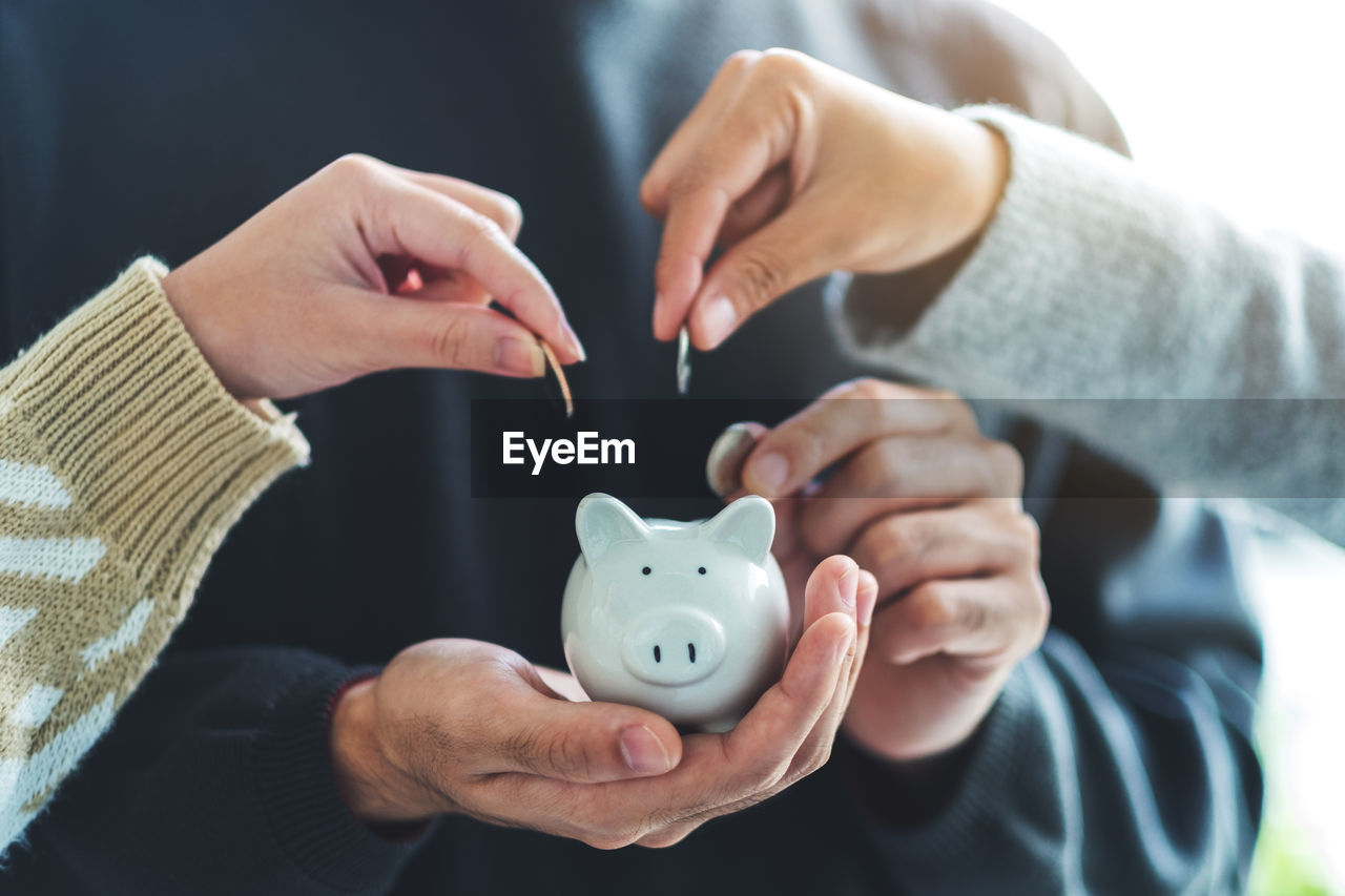 People holding and putting coin into piggy bank for saving money and financial concept