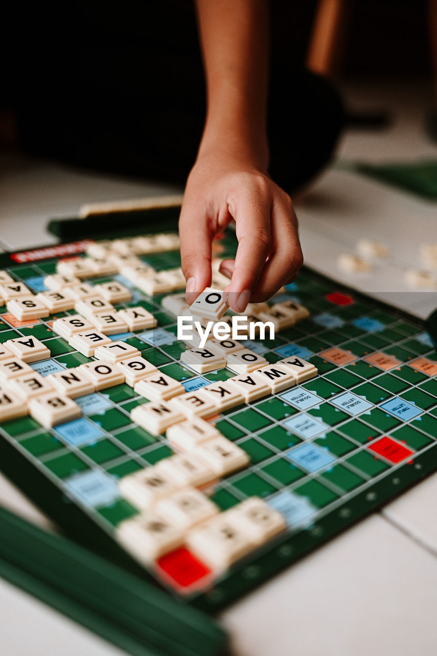 Cropped hand of person holding jigsaw puzzle on table