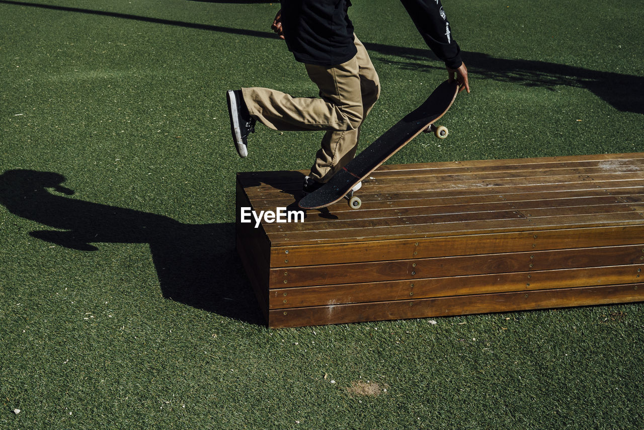 Low section of man skateboarding on wood