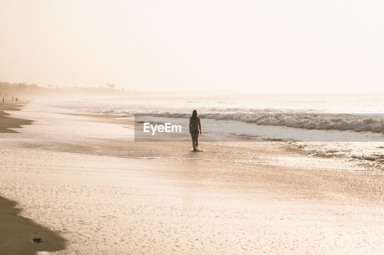 Rear view of woman at beach against sky