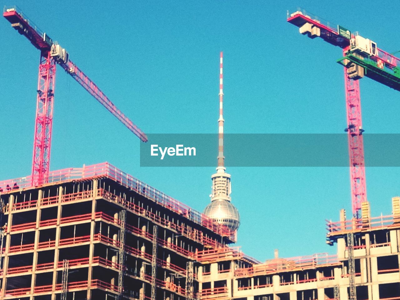 LOW ANGLE VIEW OF CRANE BY BUILDING AGAINST CLEAR SKY