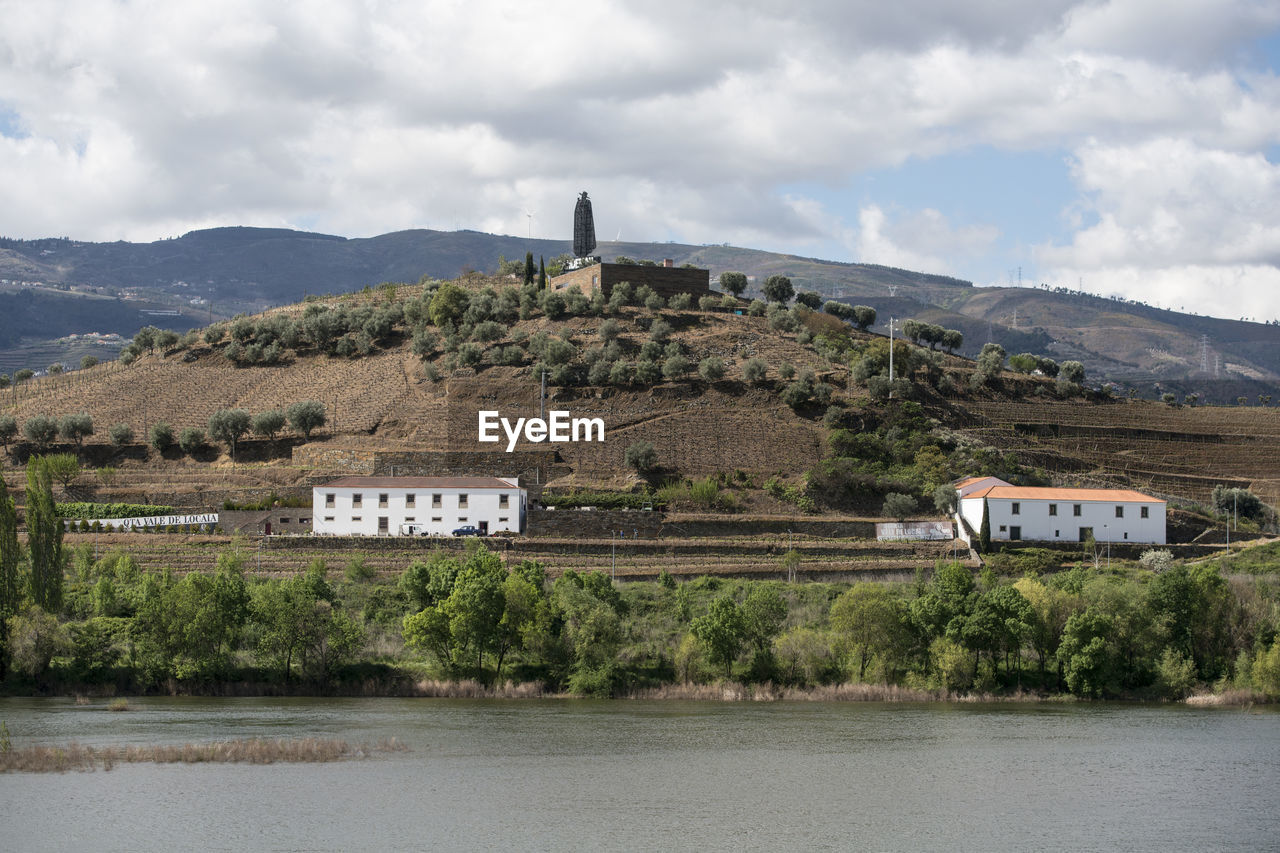 BUILT STRUCTURE BY LAKE AGAINST BUILDINGS AND MOUNTAINS