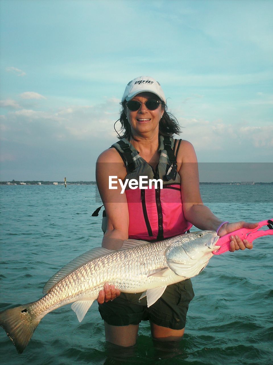 Portrait of woman holding fish while standing in sea