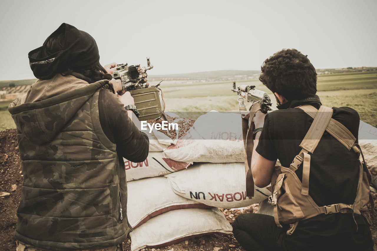 Rear view of soldiers on land against clear sky