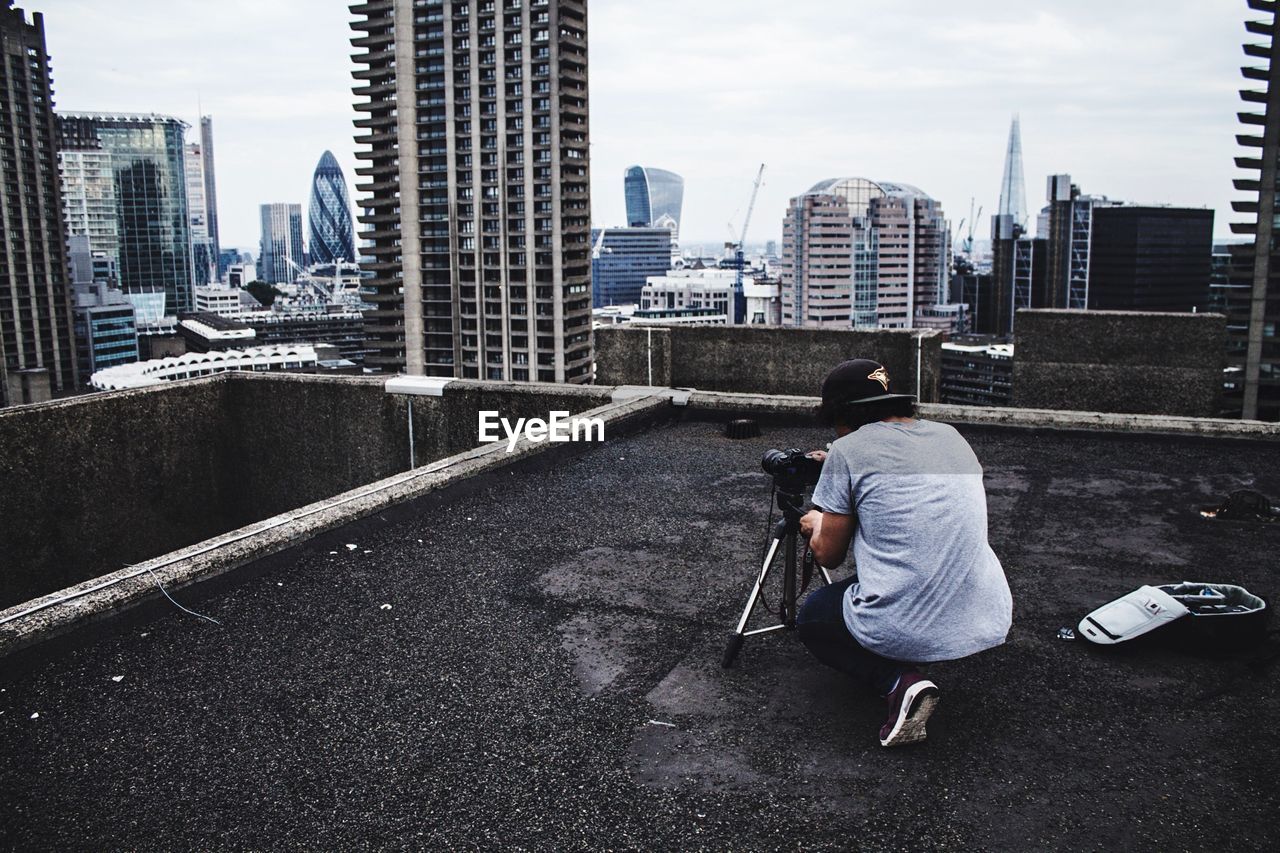 Rear view of person with camera on floor against buildings