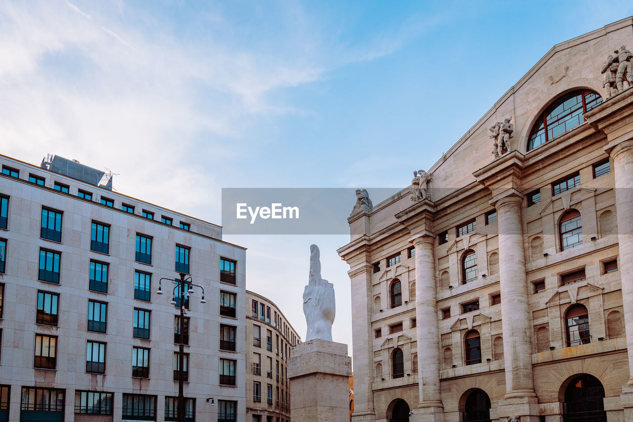 Wide angle view of piazza degli affari in milan with famous artwork in the center