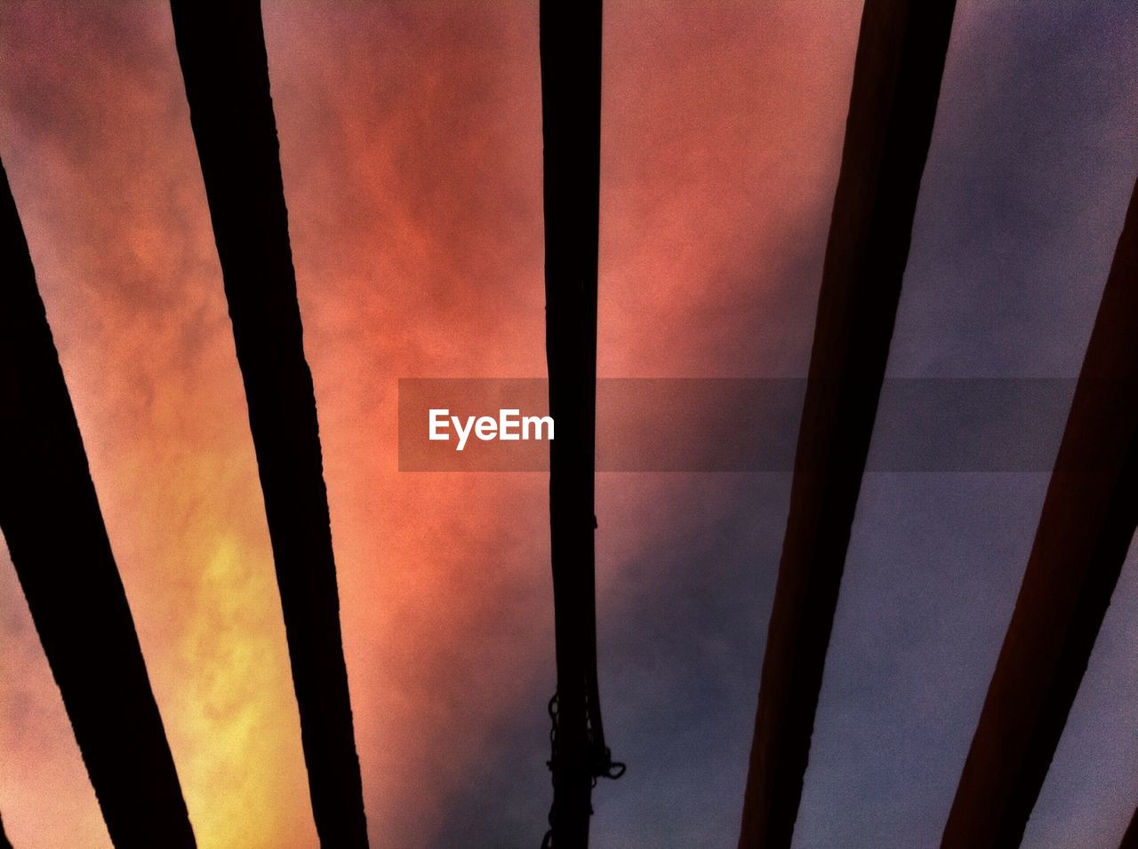 Low angle view of dramatic sky seen through wooden ceiling