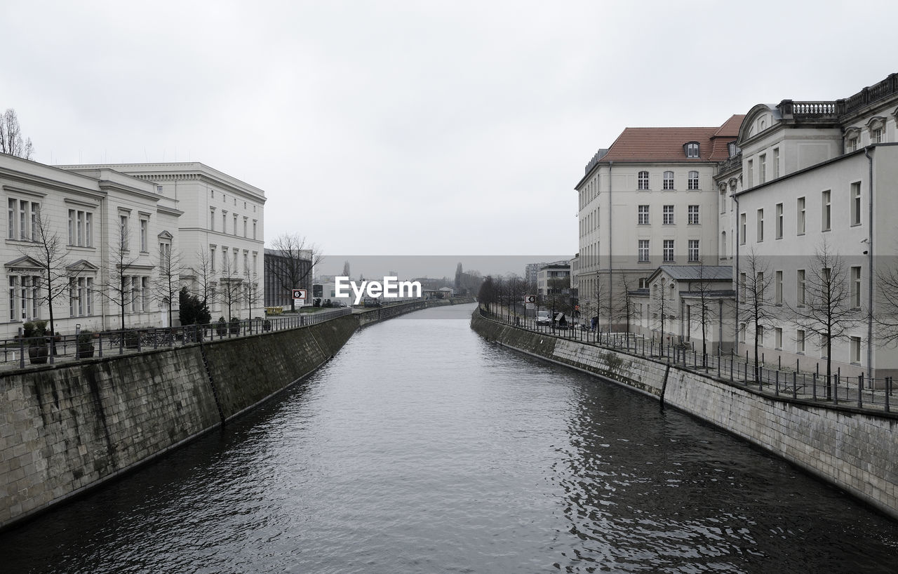 Canal amidst buildings in city against sky