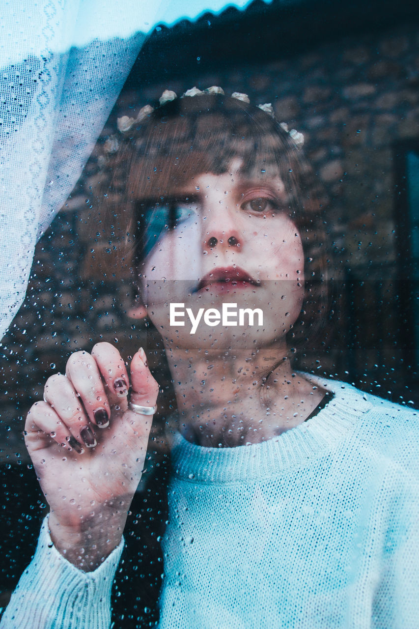 Close-up portrait of woman seen through glass window