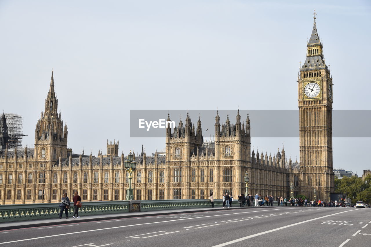 Road by big ben in city against sky