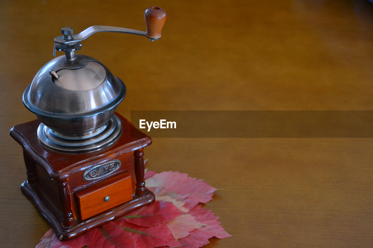 Close-up of old coffee grinder and autumn leaves on table