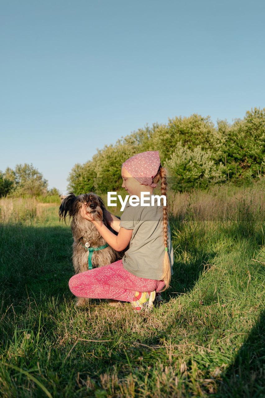 Little girl hugging playing with dog walking spending time together. child with pet in summer meadow