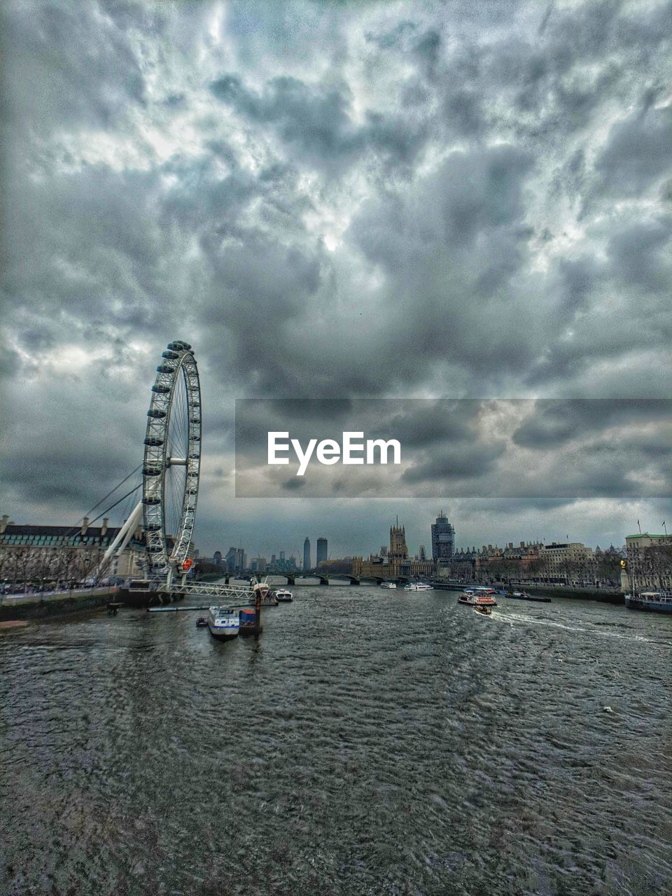 FERRIS WHEEL BY RIVER AGAINST SKY