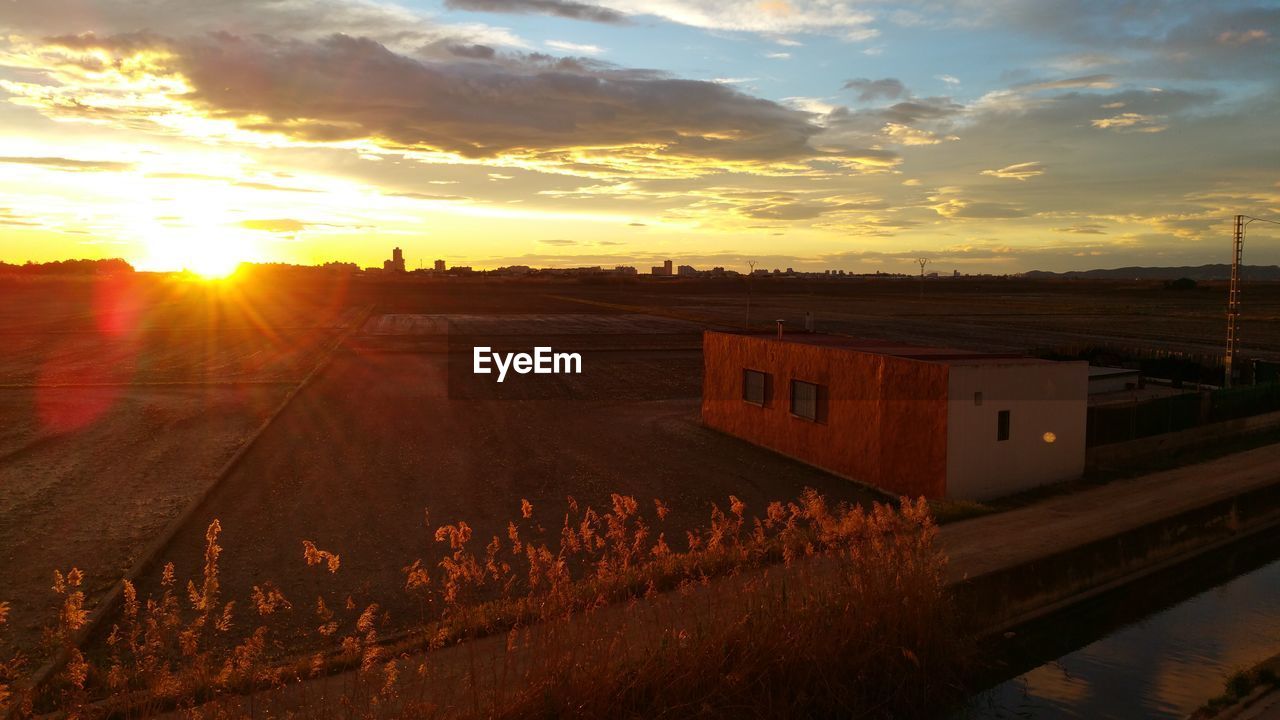 Scenic view of field against cloudy sky during sunset