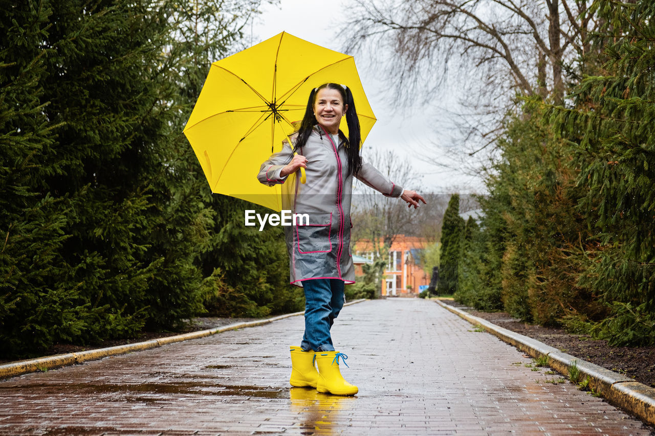 rear view of boy with umbrella walking on footpath