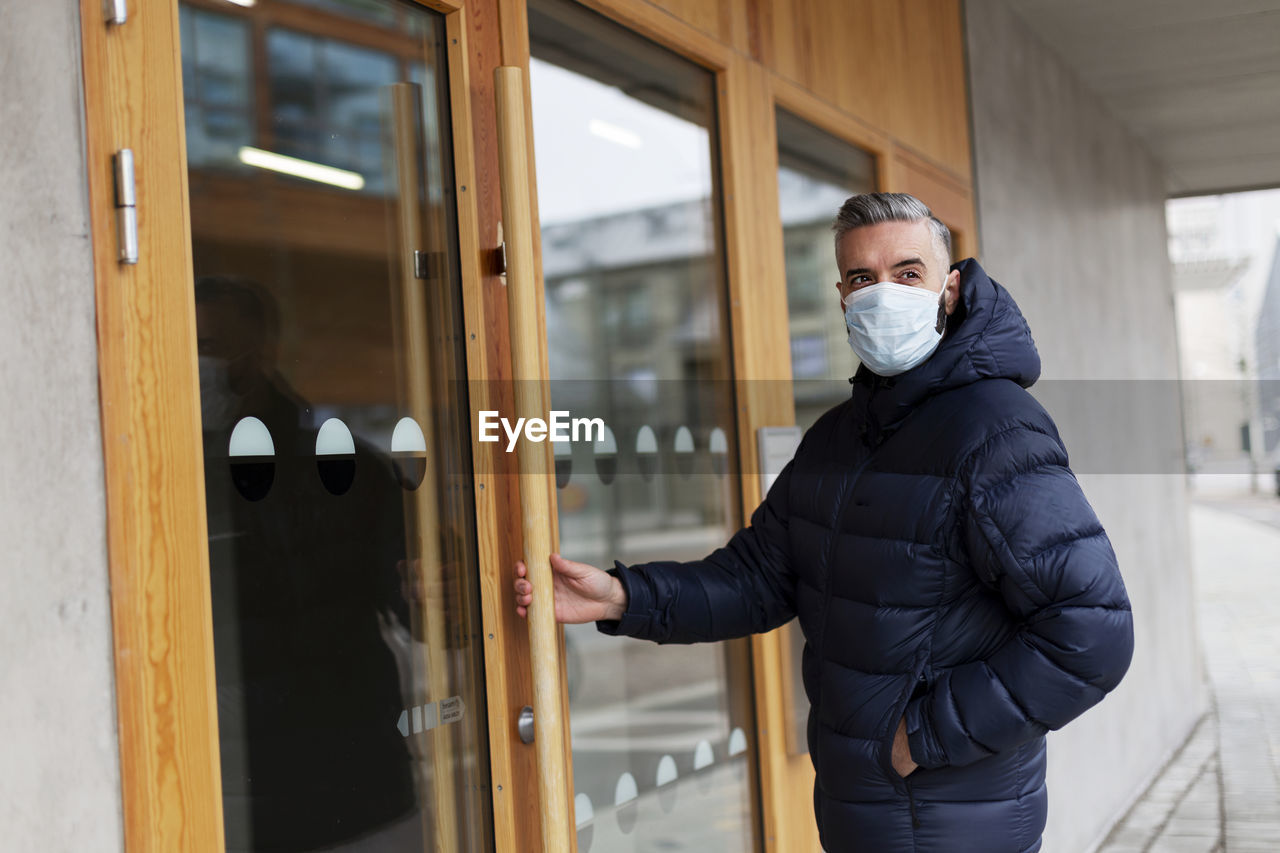 Man wearing face mask opening door