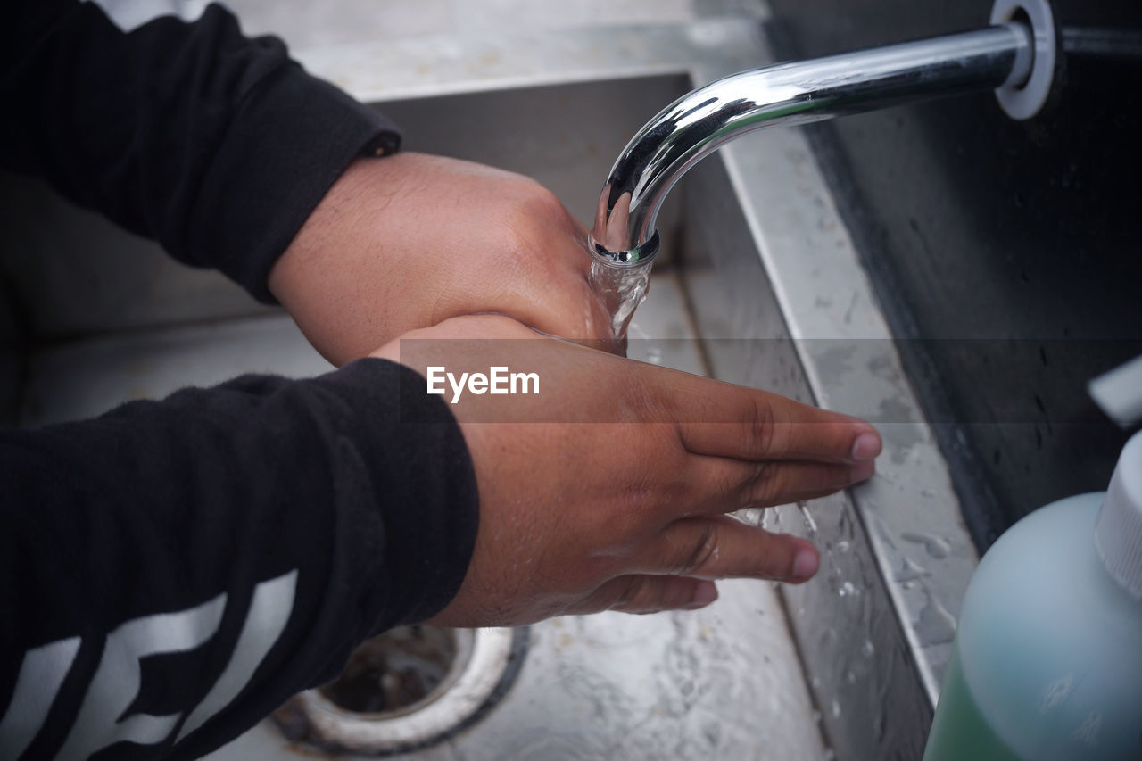 MIDSECTION OF MAN HOLDING GLASS WITH WATER IN BATHROOM