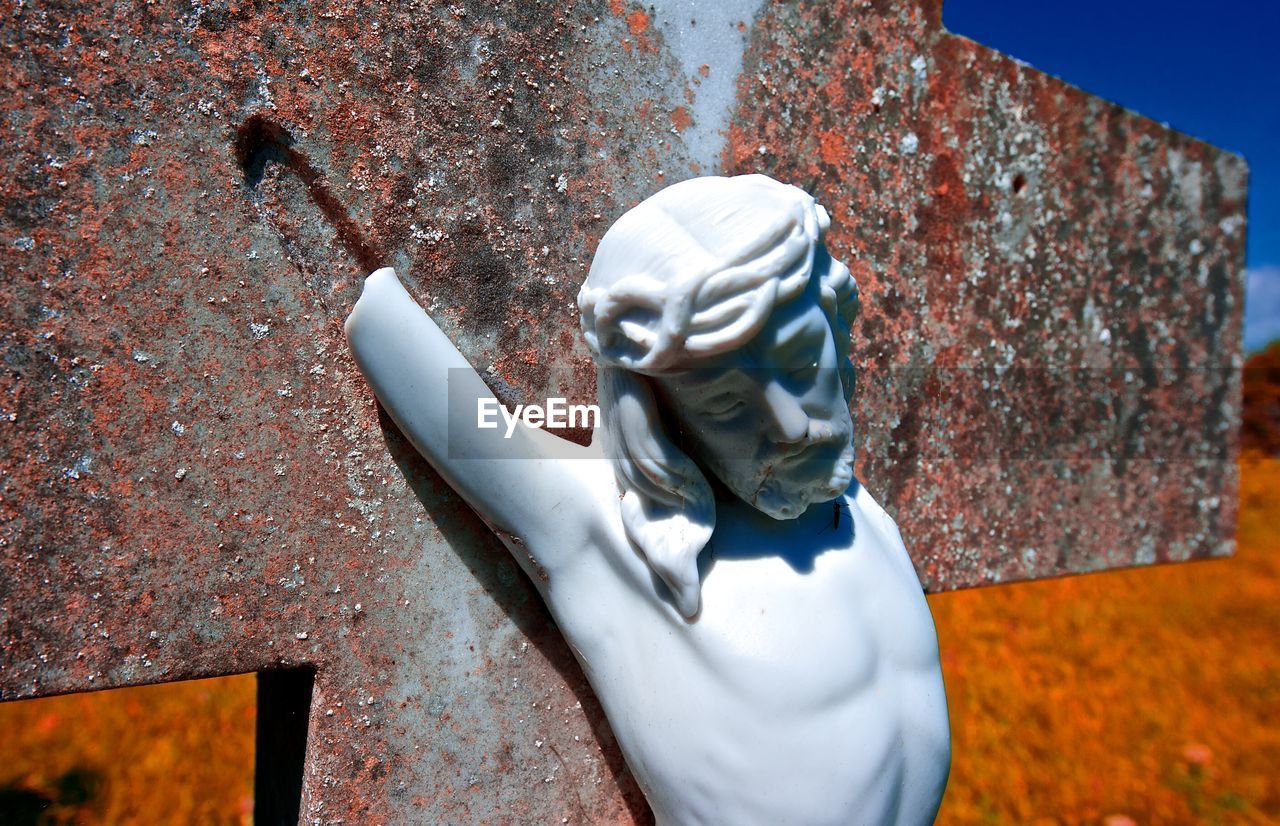 Close-up of broken jesus christ statue on cross