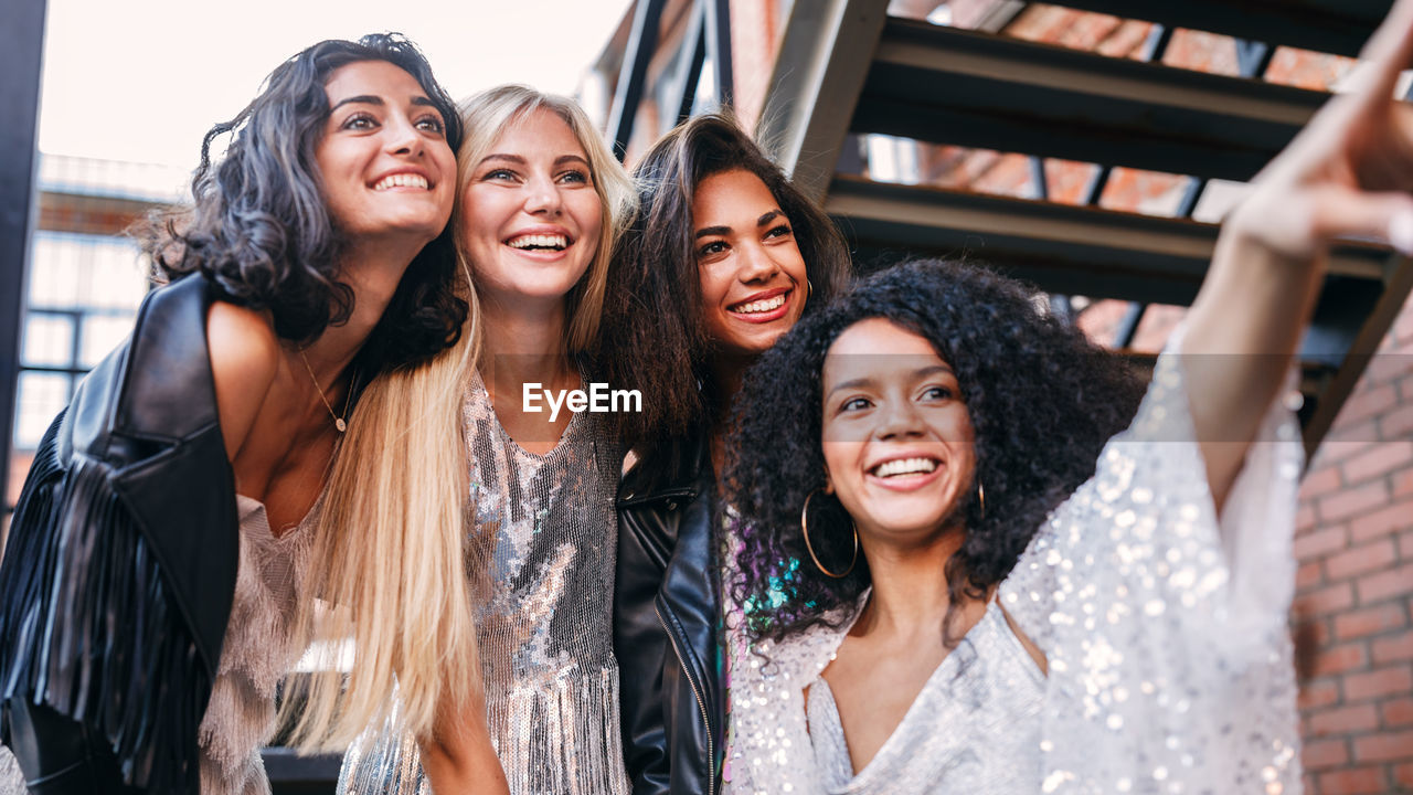 Smiling friends looking away while standing outdoors