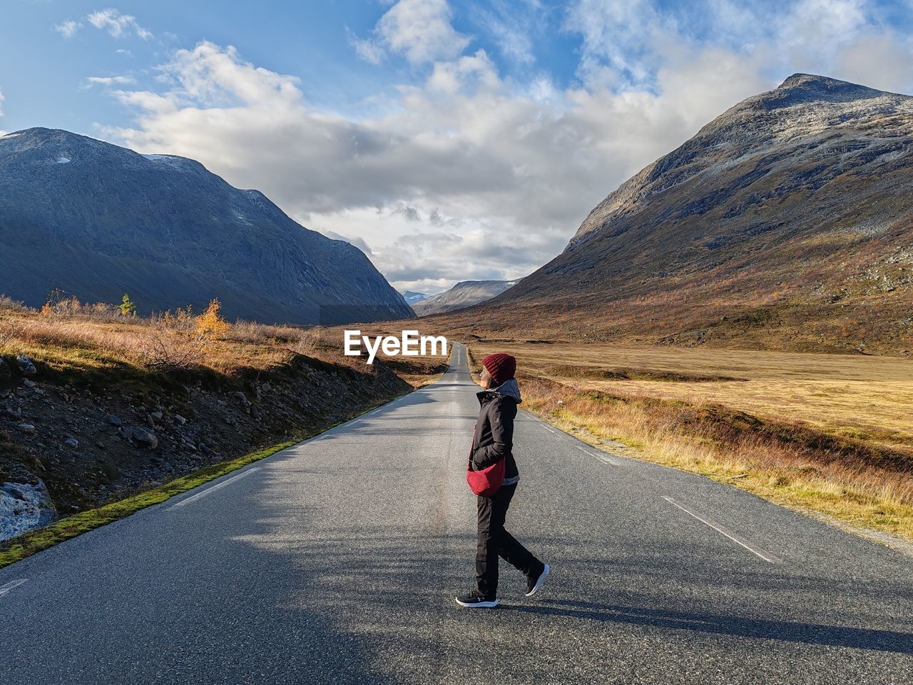 rear view of woman walking on road against mountains