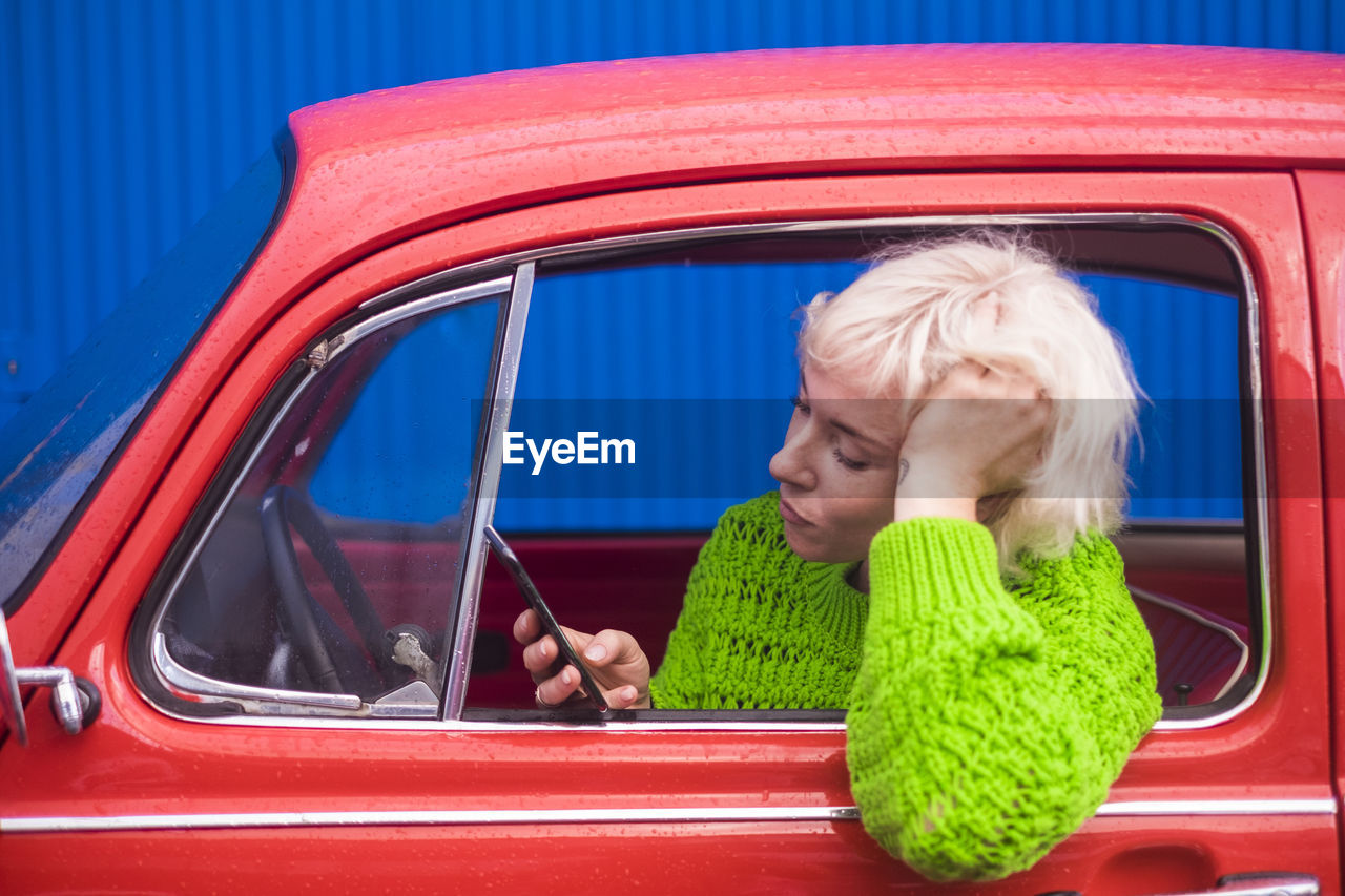 Woman using mobile phone while sitting in car