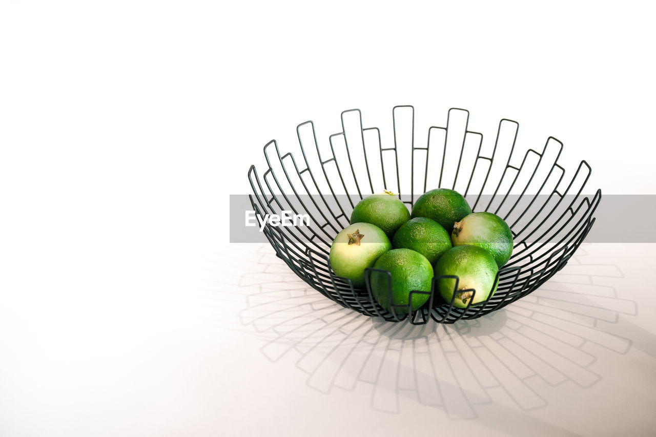 CLOSE-UP OF APPLES IN BASKET ON WHITE BACKGROUND