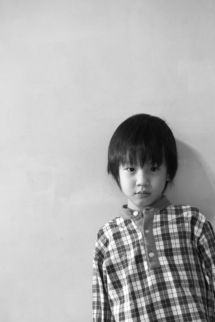 Portrait of cute boy standing against wall