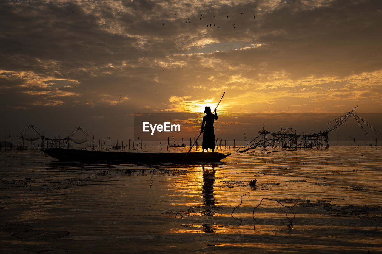 SILHOUETTE PERSON IN SEA AGAINST SKY AT SUNSET